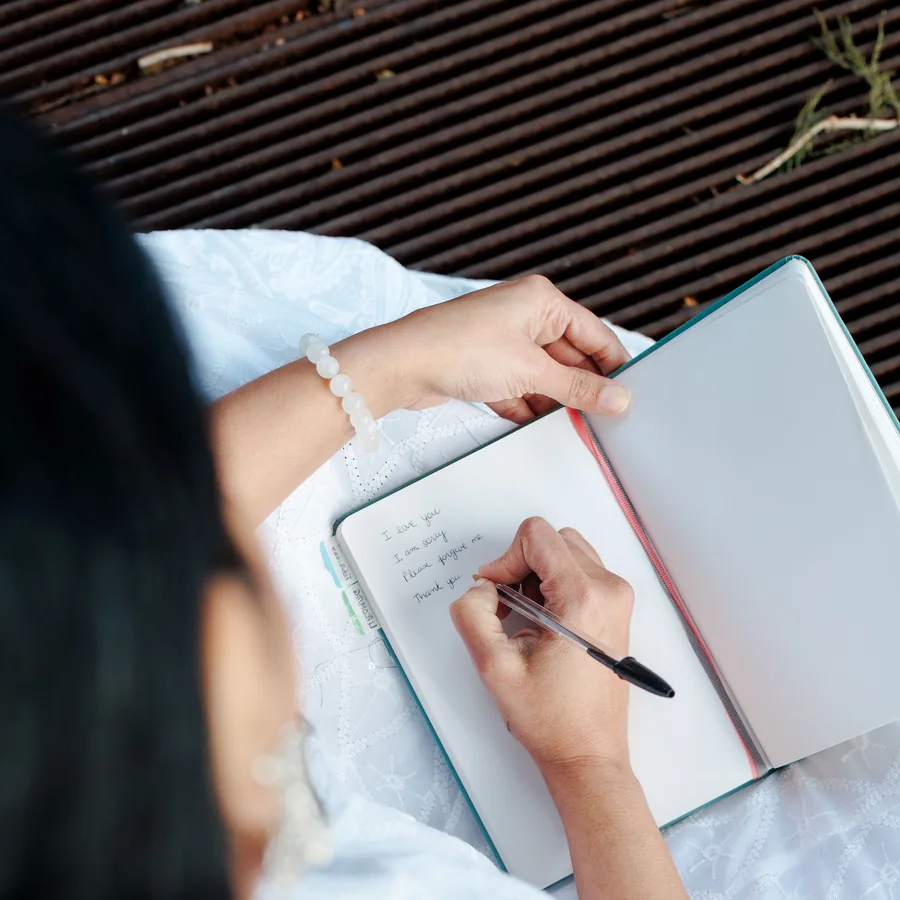 A person writing in a notebook, seen from above